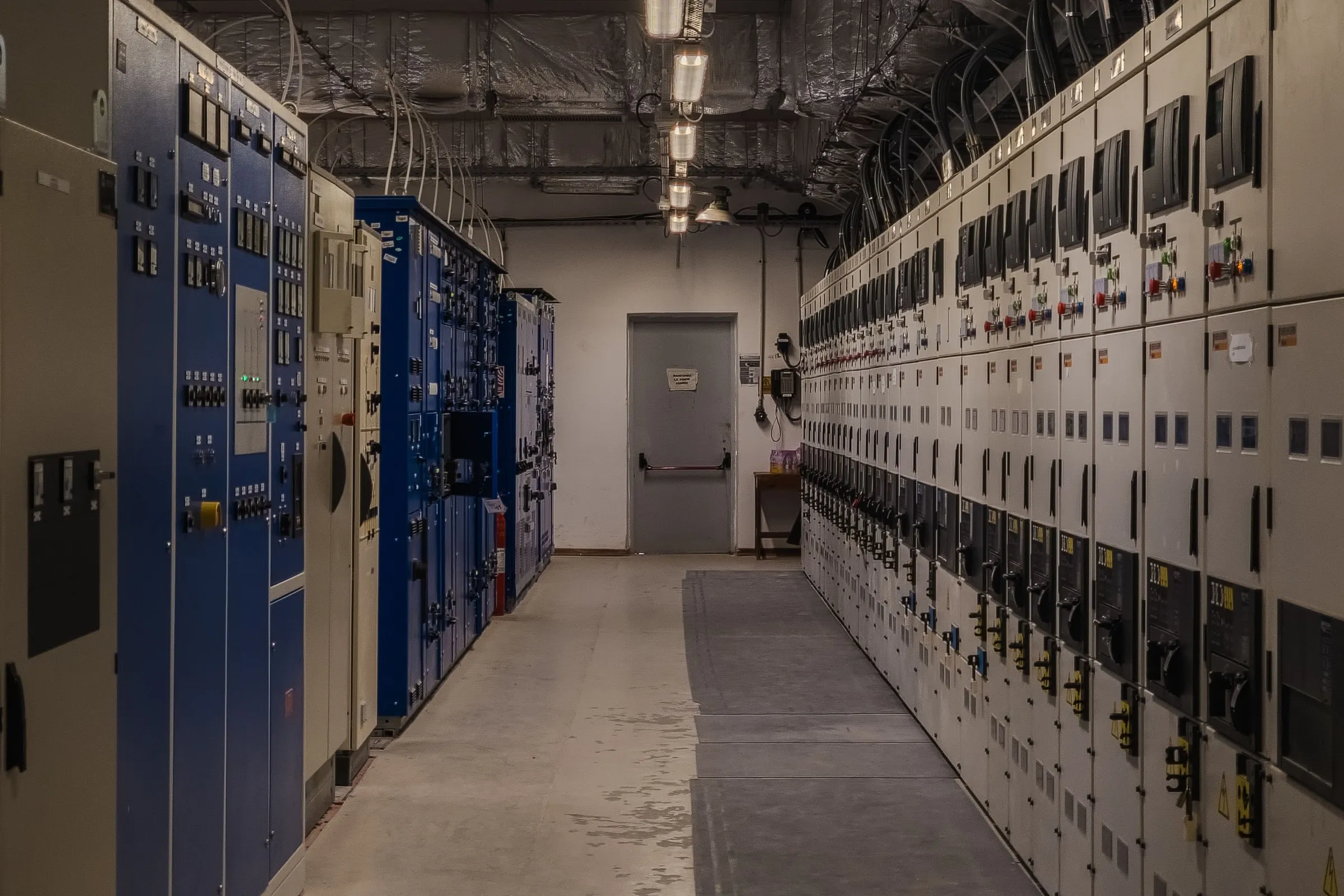 Corridoio di una cabina elettrica con lunghe file di quadri di protezione e comando